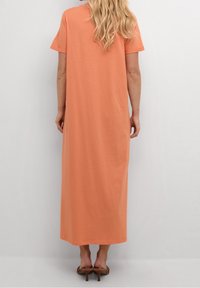 Robe maxi en coton corail doux avec des manches courtes, une coupe décontractée et un ourlet droit. Présente des détails de couture subtils et une longueur jusqu'au mollet.