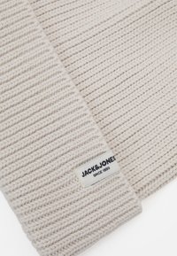 Gebreide beanie in zachte beige garen met een geribbelde textuur. Voorzien van een stoffen label met de branding "JACK & JONES" en "SINCE 1990".