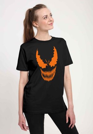 Zwarte T-shirt met korte mouwen, voorzien van een grote oranje grafische afbeelding van een dreigende gezicht met opvallende puntige kenmerken en scherpe tanden.