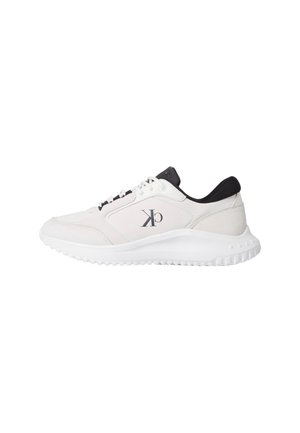 Zapatilla deportiva blanca con un acabado texturizado suave, acentos negros en el cuello, diseño de cordones y una suela de goma blanca con tracción.