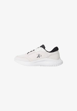 Zapatilla deportiva blanca con un acabado texturizado suave, acentos negros en el cuello, diseño de cordones y una suela de goma blanca con tracción.