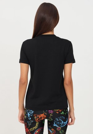 Zwart katoenen T-shirt met korte mouwen en een ronde hals. Gecombineerd met kleurrijke legging met patronen en ingewikkelde ontwerpen.