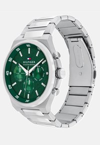 Montre en acier inoxydable argenté avec un cadran rond texturé vert, des index horaires blancs et trois sous-cadrans. Elle dispose d'un bracelet de style bande.