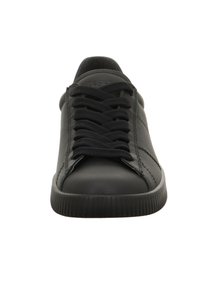 Sneaker nera a bassa altezza con lacci neri e suola rigata, vista frontalmente su uno sfondo bianco.