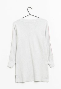 Suéter gris tejido con mangas largas, cuello redondo, aberturas laterales y detalles rojos en los hombros. Cuelga de un gancho negro.