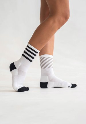Mittellange Sportsocken in Weiß mit schwarzen und grauen Streifenmustern, schwarzen Akzenten an Zehen und Ferse sowie atmungsaktiven Mesh-Bereichen.