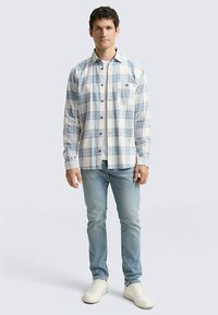 Geruit overhemd met knopen, gemaakt van zachte katoen, met blauw en wit, lange mouwen, één borstzak, gecombineerd met lichtblauwe jeans.