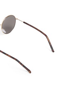 Occhiali da sole rotondi con lenti scure, sottile montatura in metallo dorato e braccia con motivo tartarugato. Presentano gommini per il naso per il massimo comfort.