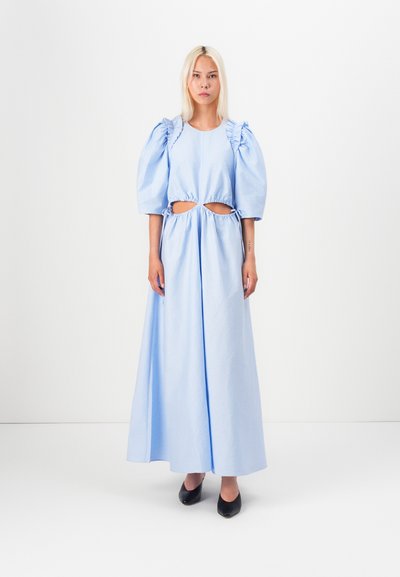 Hellblaues Kleid mit Puffärmeln, Ausschnitten an der Taille und fließender Silhouette. Glatter Stoff, knöchellang und mit einfachem Ausschnitt.
