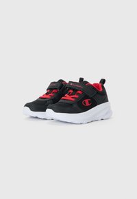 Chaussures de sport noires avec des accents rouges, tige en mesh et semelles blanches. Dotées de bandes Velcro et de lacets contrastants pour un ajustement sûr.