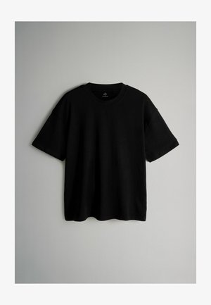 Melna īsām piedurknēm T-kreklā, kas izgatavots no kokvilnas, ar apļa kakla izgriezumu, brīvu piegriezumu un bez redzamām rakstām vai piederumiem. Gluda tekstūra.