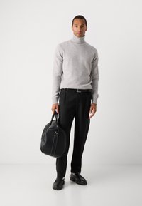 Pull à col roulé gris clair côtelé ; pantalon noir ; sac noir texturé avec des coutures blanches à la main ; chaussures noires à semelle épaisse.
