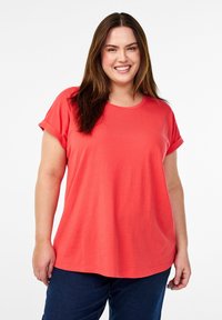 Koraalkleurig t-shirt met korte mouwen, een ronde halslijn en opgerolde mouwen, gemaakt van zacht materiaal, met een relaxte pasvorm en een gladde textuur.
