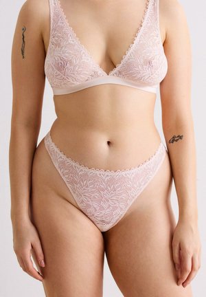 Kant bralette en bijpassende string in zachtroze. Bloemenpatroon met gegolfde randen. Semi-transparante stof met een soepele tailleband.