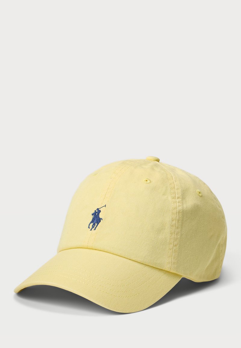 Geltonas medvilninis kepurė su išlenktu kraštu, kurio priekyje yra mėlynas siuvinėtas arklių logotipas ir ventiliacijos skylės šonuose.