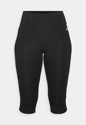 Leggings capri negros hechos de tela elástica. Cintura alta con textura suave, ajustados a lo largo de las piernas y con puños a la altura del tobillo.