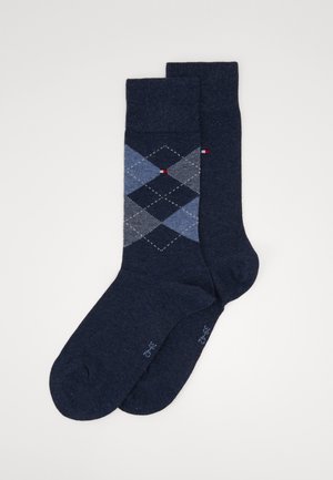 Chaussettes bleu marine avec un motif argyle aux tons bleu clair. Fabriquées dans un tissu doux avec un bord-côte. Petit détail d'accent rouge visible.