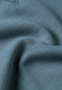 Tessuto di cotone blu chiaro con una morbida consistenza, caratterizzato da un'iconcia maglia liscia e dettagli di cucitura sottili. Ideale per abbigliamento o rivestimenti.