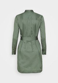 Abito camicia verde oliva a maniche lunghe con cintura, vista posteriore, caratterizzato da pieghe e polsini con bottoni su sfondo bianco semplice.