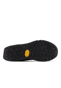 Suela de zapato de goma negra con un patrón de autohexágonos y un logo amarillo de Vibram. Construcción sólida con elementos de agarre texturizados.