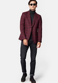 Bordowy marynarka w kratę o dopasowanym kroju, noszona na czarnym golfie. Połączona z czarnymi zniszczonymi dżinsami i ciemnymi botkami za kostkę.