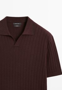Burgandy bomullspolo med korta ärmar, med vertikal ribbad textur och en mjuk krage. Etiketten säger "Massimo Dutti."
