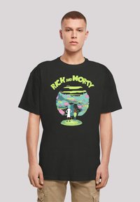 Fekete pamut póló, amelyen egy színes grafika látható Rick és Morty rajzfilm karaktereiről egy halszarin, élénk betűtípussal a tetején.