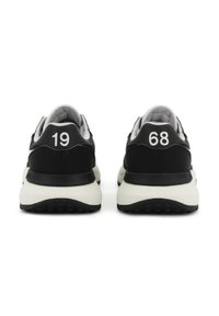 Sneakers neri con suola bianca a contrasto. La vista posteriore mostra i numeri 19 e 68 in bianco, materiale testurizzato e design arrotondato.
