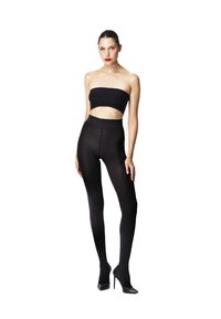 Leggings neri a vita alta abbinati a un top bandeau nero, caratterizzati da una texture liscia e un design aderente, indossati con tacchi alti neri.