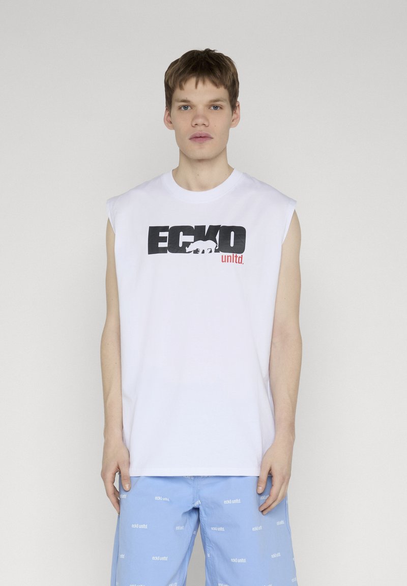 Jeune homme portant un débardeur blanc ECKO unltd. et un short bleu clair avec de petits logos blancs répétés ECKO unltd.