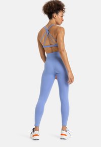 Lichtblauw activewear-set met een sportbh met straps die gekruist zijn op de rug en high-waisted leggings, gemaakt van rekbare stof.