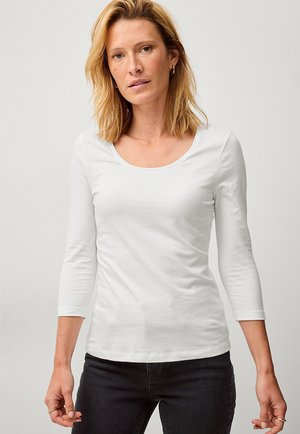 Bílý dlouhý rukáv top s kulatým výstřihem, vyrobený z jemné bavlny. Přiléhavý design, hladká textura a minimalistický styl.