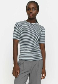 Gestreiftes T-Shirt mit kurzen Ärmeln in Marineblau und Weiß, mit rundem Ausschnitt und figurbetontem Design, kombiniert mit grauen maßgeschneiderten Hosen.