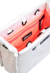 Witte nylon tas van binnen met roze voering, voorzien van een ritsvak en een merklabel. Inclusief zwart hardware en getextureerde accenten.