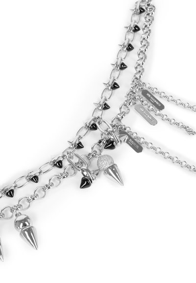 Zilveren ketting met spikes en zwarte accenten, met meerdere strengen en decoratieve elementen, waaronder een gestoken hanger.