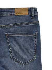 Denim bikses vidējā zilā mazgāšanā ar dzeltenu šuvju. Iespējama ādas etiķete uz jostas un klasiskā kabatu dizains.