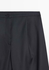 Zwarte broek met een slanke tailleband, voorzien van een sluiting met een knoop aan de voorkant, scherpe plooien en een gladde stoftextuur.