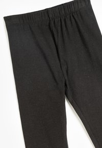 Svarta bomullsleggings med elastisk midja, slät textur och en åtsittande design utan mönster eller dekorationer.