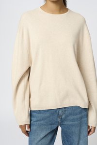 Beige sweatshirt med rund halsringning, vida ärmar och avslappnad passform, tillsammans med ljusblå denimjeans. Mjuk textur och minimalistisk design.