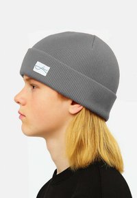 Gray ribbed beanie made of knitted fabric, featuring a folded cuff and a small white brand tag on the side.