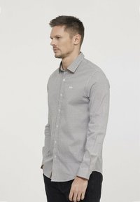 Chemise à boutons gris avec un motif géométrique, dotée d'un col pointu et de manches longues. Marquage subtil sur la poitrine, texture lisse.
