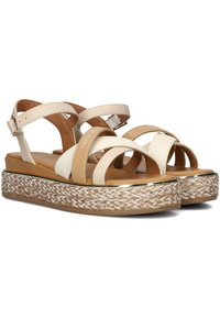 Sandali con fascia beige e bianca, caratterizzati da una piattaforma in espadrille intrecciata, con rifiniture dorate e cinturino alla caviglia regolabile.