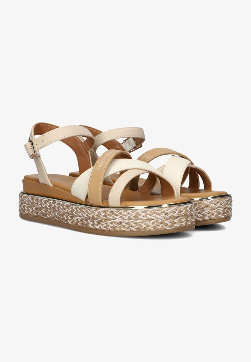 Sandali con fascia beige e bianca, caratterizzati da una piattaforma in espadrille intrecciata, con rifiniture dorate e cinturino alla caviglia regolabile.