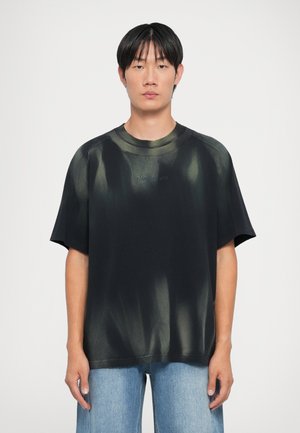 Svart oversized T-skjorte med grønn tie-dye-mønster, rund halslinning og kortermet. Har brodert logo på brystet.