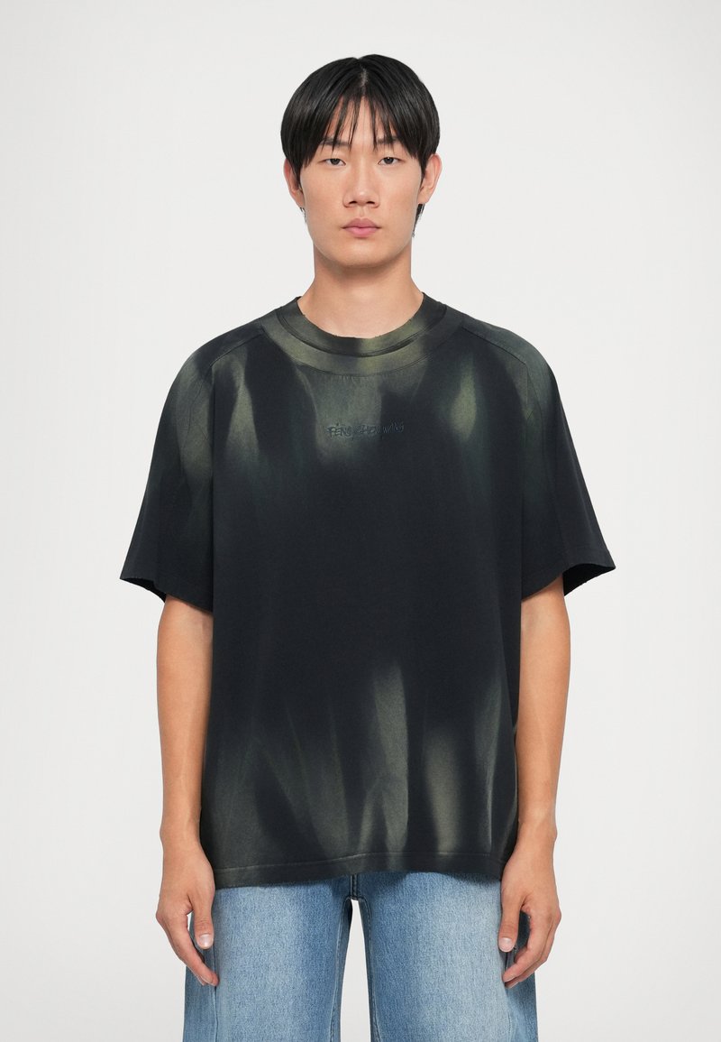 Mustardas suuruses must T-särk rohelise sidrunihalli mustriga, ümar kaelus ja lühikesed varrukad. Ees on tikandiga logo.