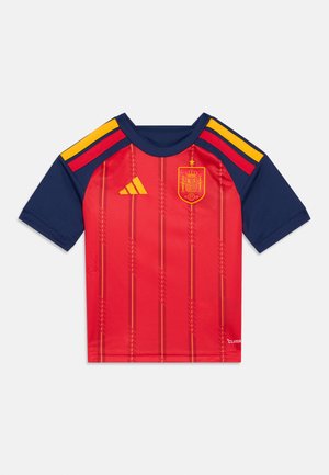 Tricou scurt cu mâneci roșii, cu dungi verticale, accente bleu marin, logo auriu și culorile steagului spaniol pe umeri. Fabricat dintr-un material neted și ușor.