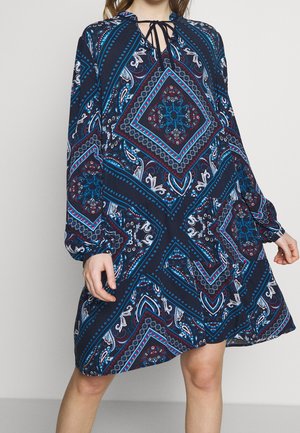 Robe à manches longues en marine avec un motif paisley intricant, mettant en avant des formes géométriques en rouge et turquoise, et un décolleté avec une ouverture en forme de clé et des liens.