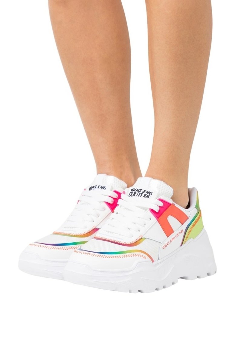 Baskets blanches avec des accents multicolores en rose, orange et vert. Semelle épaisse, design à lacets et détails de couture contrastés.