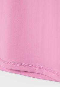 krupni plan ružičaste tkanine s detaljnim šavovima duž ruba, pokazujući glatku teksturu i uredan rad šavova.