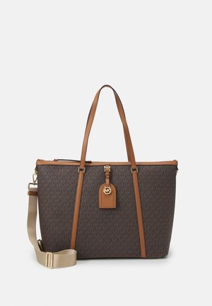 Sac cabas marron avec garniture en cuir beige, deux poignées, bandoulière réglable beige et pendentif logo MK doré sur l'étiquette avant.